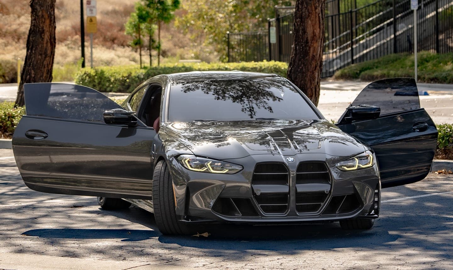 Black BMW M4 with both doors open during an interior detail